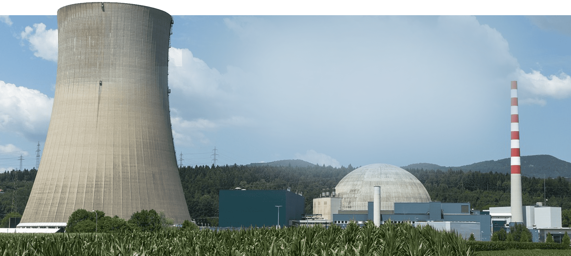 A large green field with a power plant in the background.