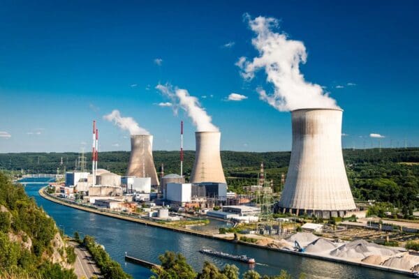 A large power plant with smoke coming out of the stacks.